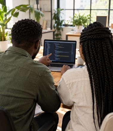 Two developers reviewing code together at a laptop